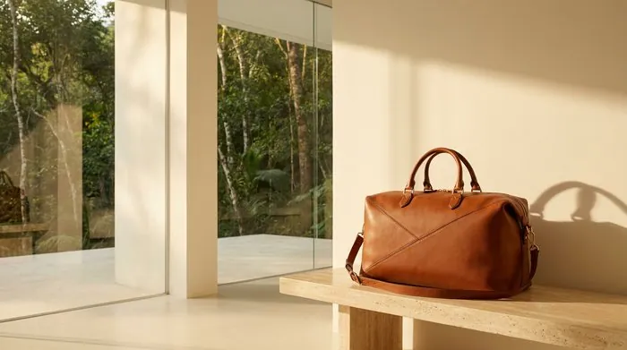 Le Voyageur, bolsa de viagem em couro cognac diante da mata